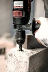 Carpenter using electric drill for his job in carpentry workshop