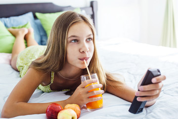 Girl drinking juice and watching tv in bedroom