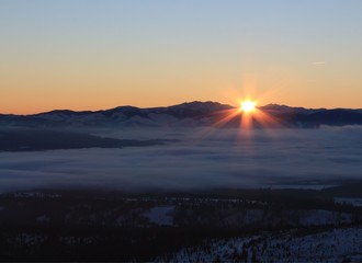 Sunset over mountains with fog.