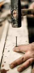 Carpenter using hammer for his job in carpentry workshop