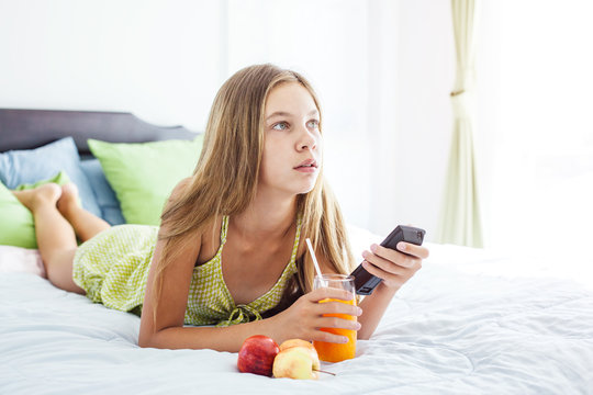 Girl drinking juice and watching tv in bedroom