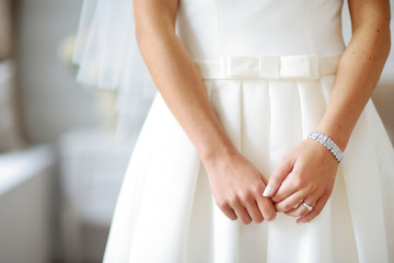 Obraz na płótnie Canvas Bride's hands on beautiful white wedding dress
