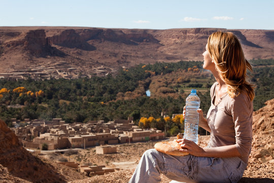 femme assise sur une montagne devant un village marocain