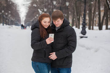 man and woman on a winter outing to the gadget in his hands