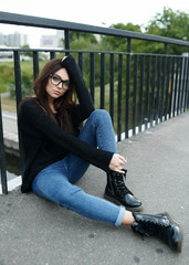 Hipster woman sitting on the road in the summer in the city. The concept of lifestyle and fashion