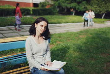 Obraz premium young woman reading a book sitting in the park