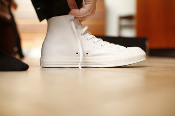 Dettagli odi scarpa bianca appena indossata con mani che mettono apposto i lacci