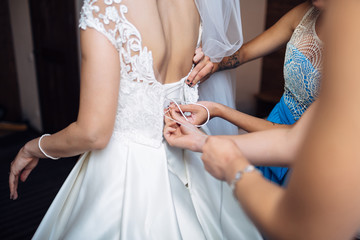 Obraz na płótnie Canvas The bridesmaids helping to wear a wedding dress