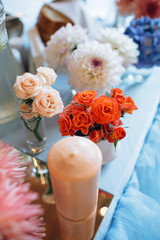 The candles and vases with flowers  stand on the wedding table