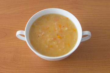 Polish cabbage soup in a white bowl on wooden background. Soup knows in Poland as Kapusniak.