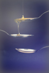 Honey pouring from spoon against a dark background