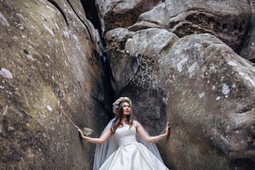 The beautiful bride stands near stones