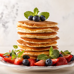 Homemade pancakes with berries and fruit on a white background.