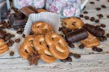 Some pieces of chocolate, chocolate sweets, shortbread cookies, coffee beans and star anise on a white wooden background