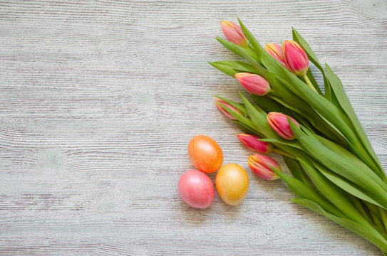 Easter eggs and tulips with a white card on the vintage wooden background