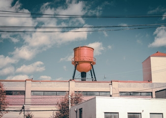 Industrial building with water reserve on roof. red water tower on top of office building. Isolated water tower structure. Architecture detail with water tower. Abstract architectural design and art. 