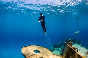 Freedivers swimming through a large underwater shipwreck