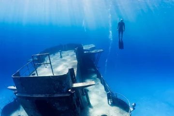 Fototapeten Freedivers swimming through a large underwater shipwreck © whitcomberd
