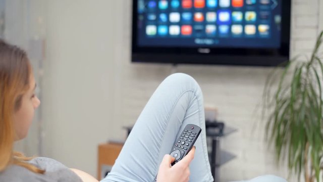 Smart tv and woman pressing remote control.