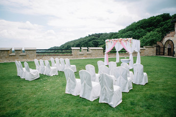 arch and white chairs for the wedding ceremony standing outdoors