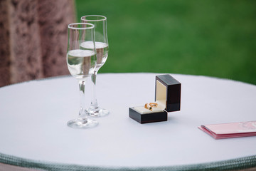 box with rings and glasses with champagne standing on the table