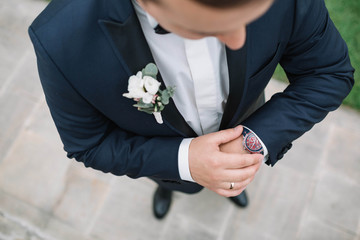 young groom in blue jacket looks at his wrist watch