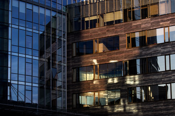 Fototapeta premium Illuminated by sun empty office building windows in the sunset. Window pattern in blue and brown colors.