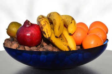 Obstschale mit Bananen, Orangen, Äpfeln, Granatäpfel, Walnüssen
