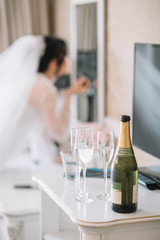 Three glasses with champagne stand near a bottle