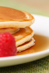 Pile of Pancakes with blueberries and raspberries and maple syrup dripping