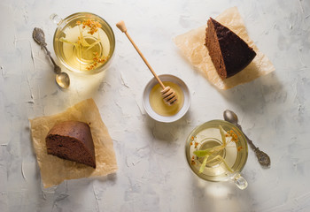 Sliced homemade chocolate pie on white and grey stone background. Herbal linden tea and honey.