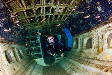 Fotobehang A SCUBA diver explores the upturned cabin of an underwater aircraft wreck © whitcomberd