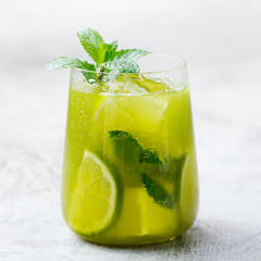 Matcha iced green tea with lime and fresh mint on a marble background. Copy space