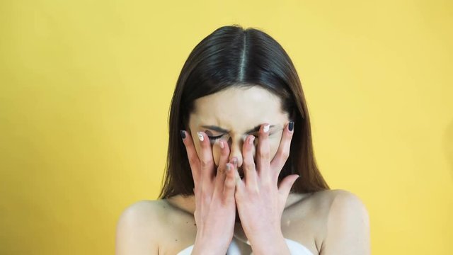 Portrait of the girl with emotion of crying on yellow background in 4K