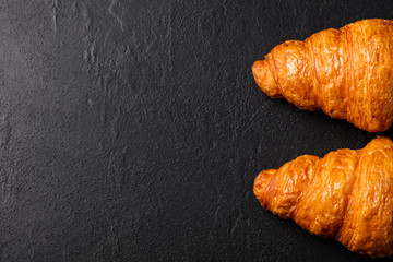 Fresh croissant on a black slate background. Top view. Copy space
