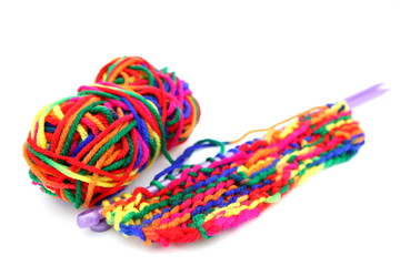 Bright multi-colored colourful knitting wool or yarn with knitting needles on white background