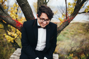 The handsome groom sits on the bench