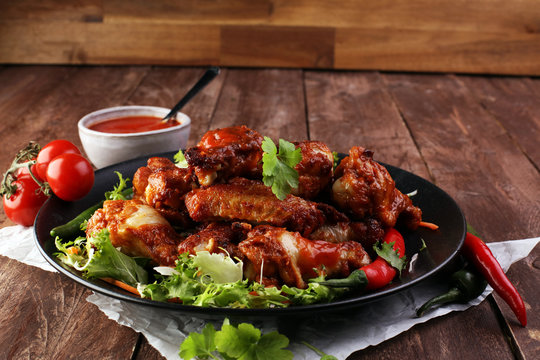 Barbecue Chicken Wings Close Up On Wooden Tray With Red Spice Sauce And Salad