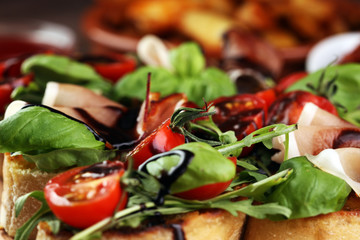 Italian antipasti wine snacks set. Cheese variety, Mediterranean olives, pickles, Prosciutto di Parma, tomatoes, artichokes and wine in glasses