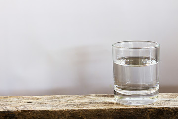 Clean drinking water is in the glass on the wooden floor.
