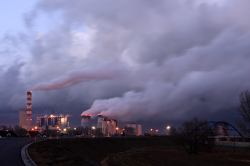 Dymiące kominy elektrowni węglowej w Opolu wieczorem.