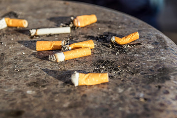 Cigarette in outdoors ashtray with sand closeup , selective focus