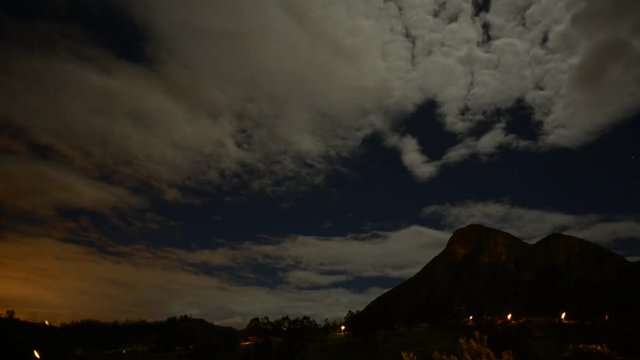 Time lapse of clouds moving in night sky over mountains
