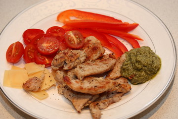 Slices of roast turkey with tomato, red pepper, slices of cheese and pesto.