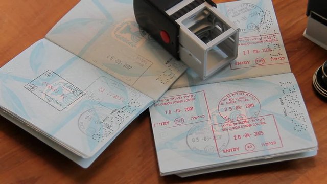 Passports and Stamps on Brown Wooden Desk.