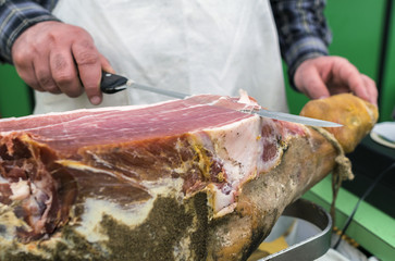 Slicing of italian dry-cured ham prosciutto