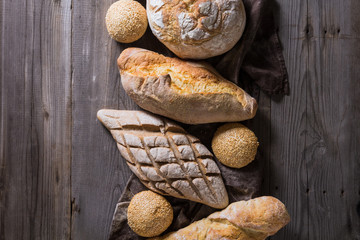 Several types of fresh bread lying on an old wooden table