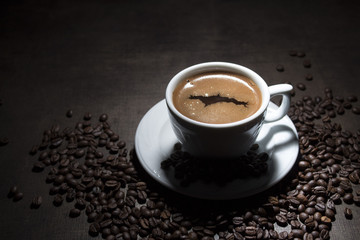 Cup of coffee with grains on wooden table on dark background