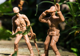 Two tan soldiers outside one with a binocular