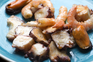 Tasty seafood salad on blue plate. Horizontal shoot.